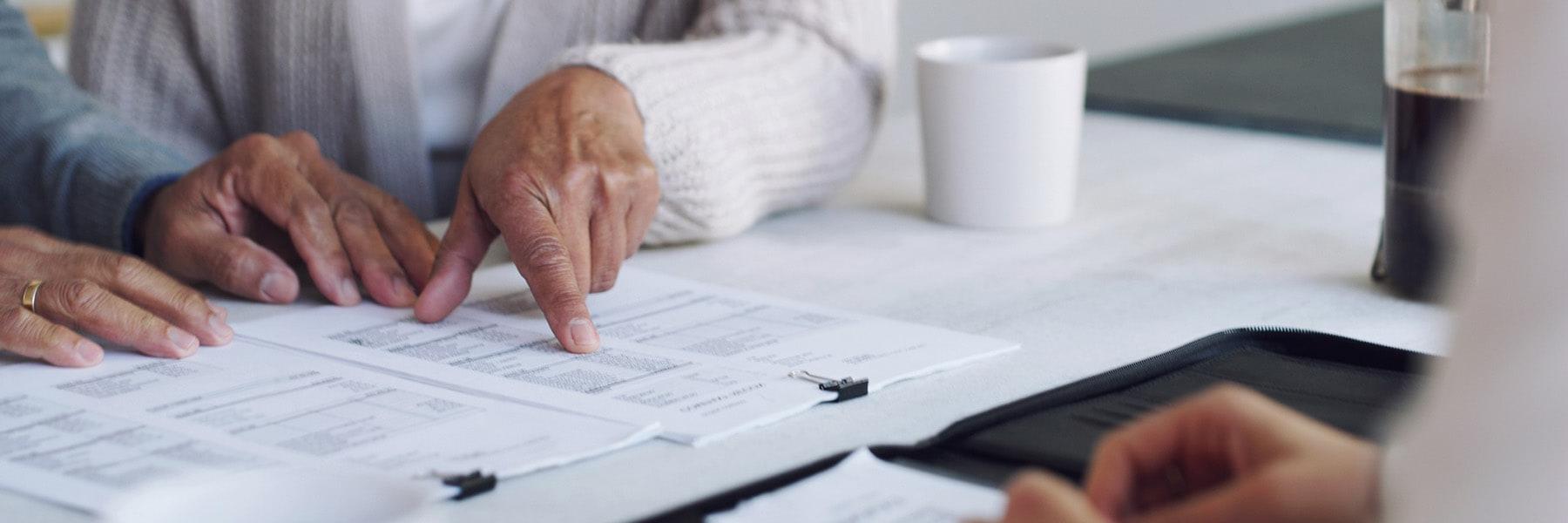 hands touching financial documents next to coffee cup.